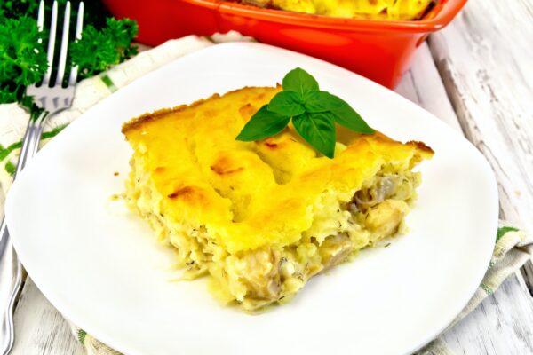Gratin potato with fish in plate on light board