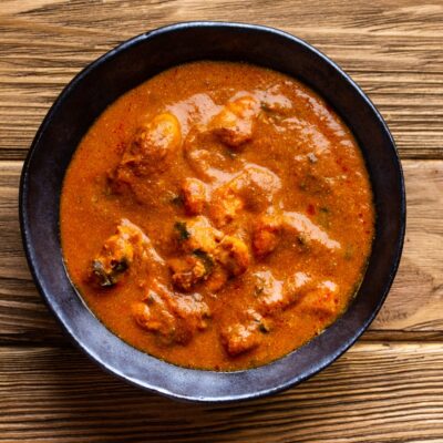 Indian chicken curry with tomato gravy on wooden rustic background