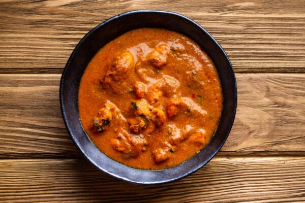Indian chicken curry with tomato gravy on wooden rustic background